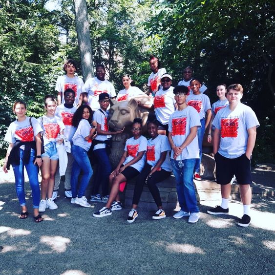 camper standing in matching t-shirts around lion statue