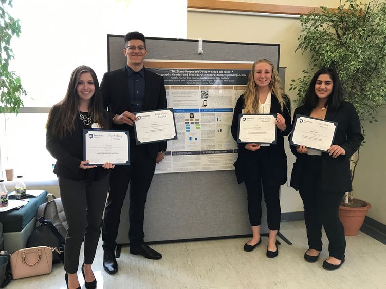 Four students posing in front of research poster