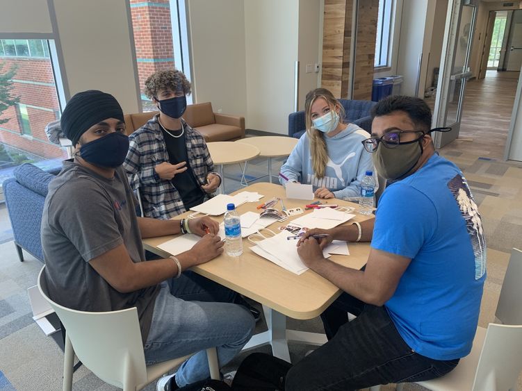 Four students sit around a table decorating gift bags.