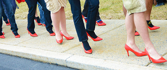 Men wearing red high heels walking around campus