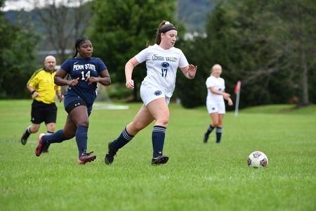 woman dribbling soccer ball down field